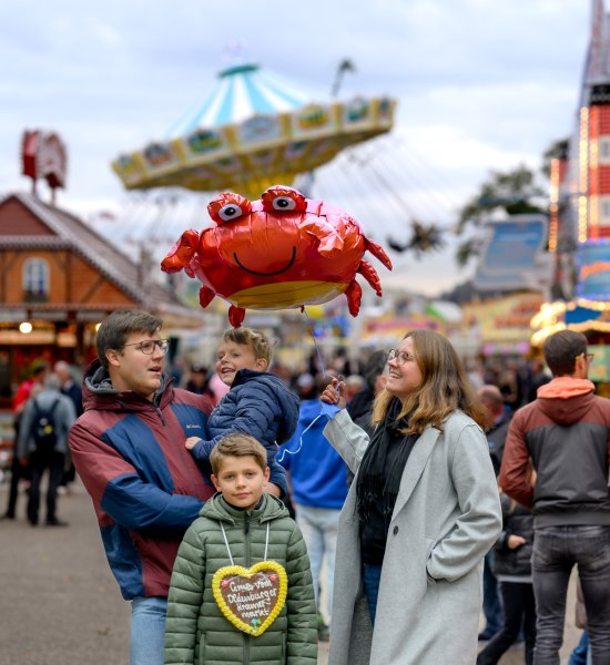 Bezoek aan de Kramermarkt in Oldenburg Gezin met vader, moeder en twee zoons op de Kramermarkt in Oldenburg, met een peperkoekhart en een ballon.